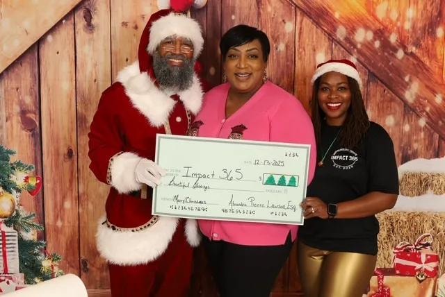 Atoundra Pierre Lawson presenting a mock check at the Impact 365 holiday event